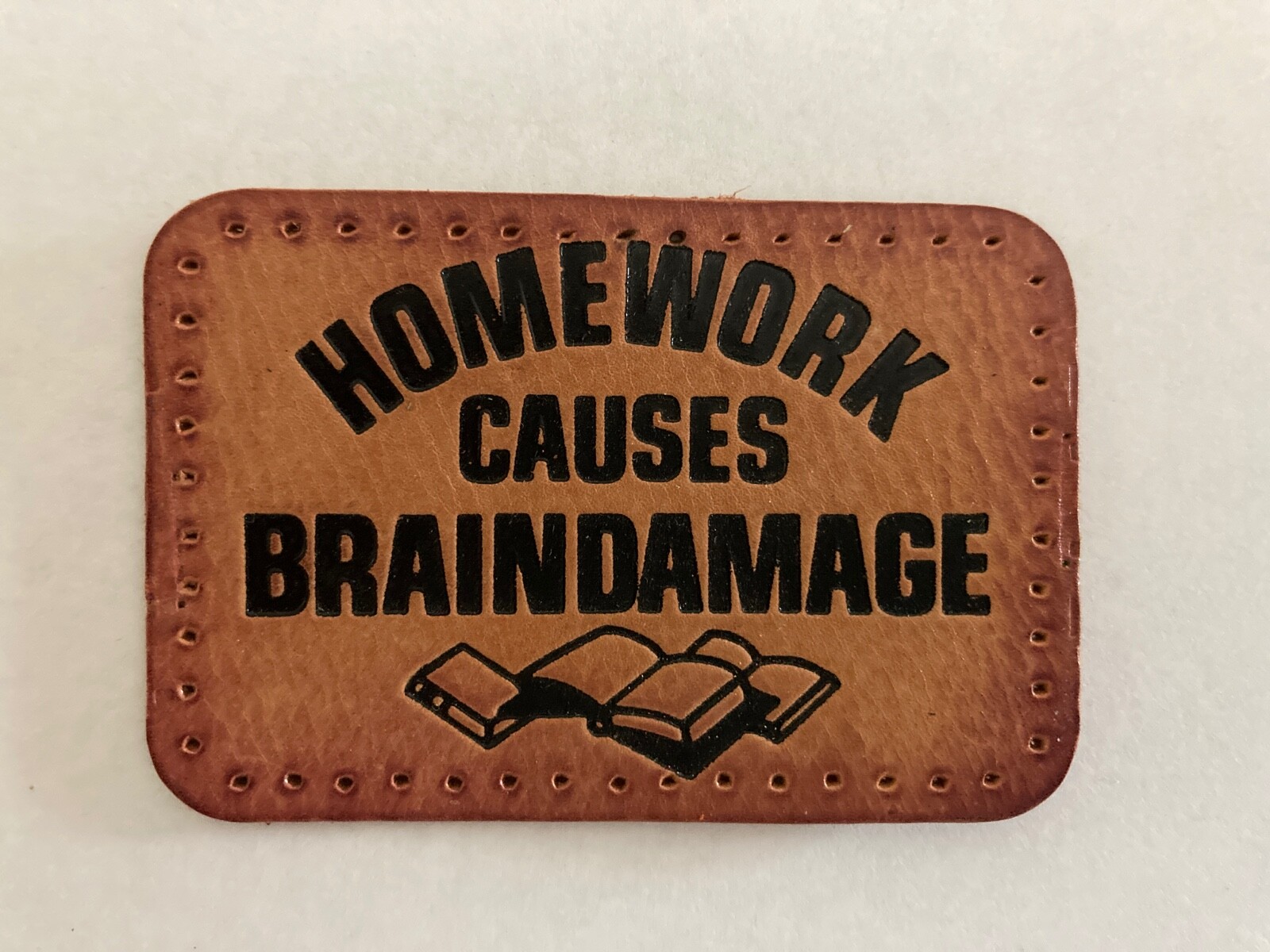 “HOMEWORK CAUSES BRAINDAMAGE” LEATHER PATCH – FUNNY LEATHER PATCH WITH HOLES